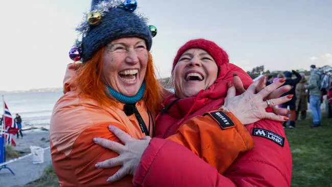 To glade kvinner klemmer og ler sammen etter et forfriskende bad på Ølbergstranda